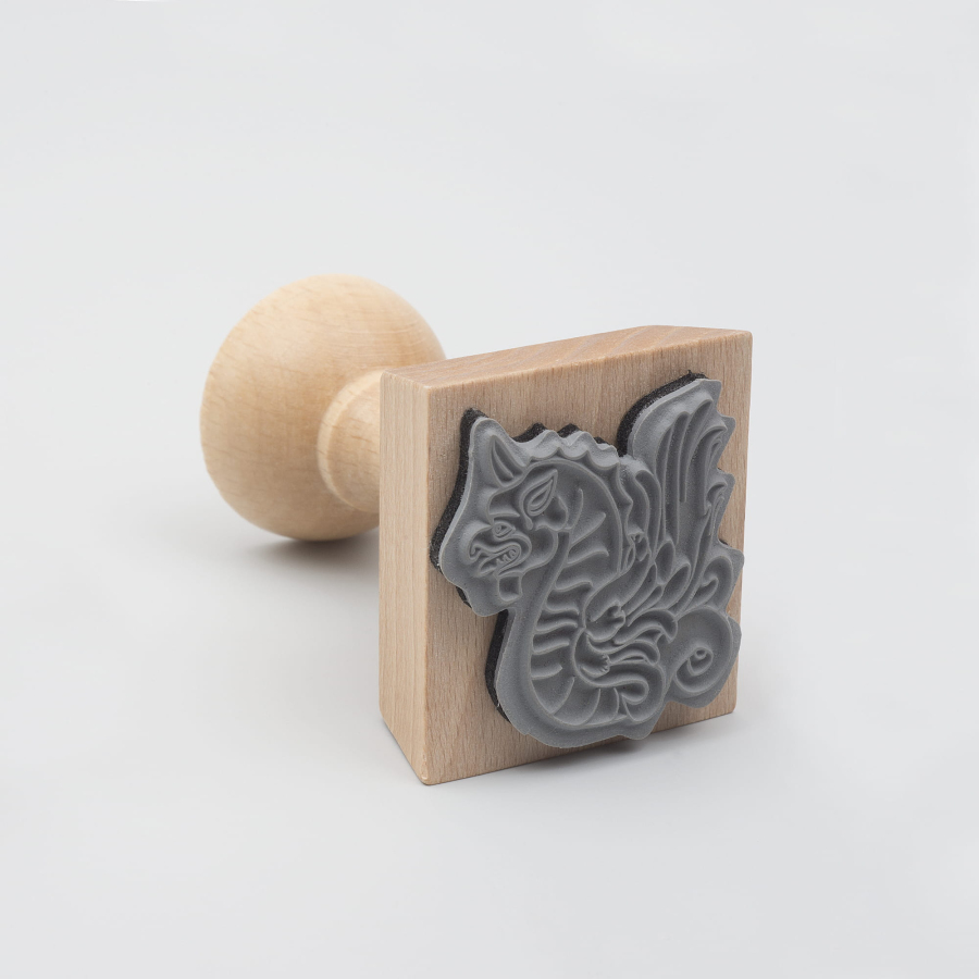 Drewniany stempel z pieczątką w kształcie smoka.