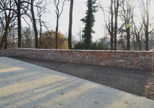 Ceglany mur w otoczeniu drzew.