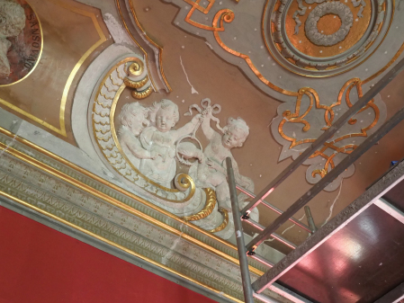 Dekoracja malarstwa i rzeźbiarska na suficie historycznego wnętrza Pałacu Wilanowskiego przedstawiająca putta trzymające przewiązaną na kole z papugą wstążkę.