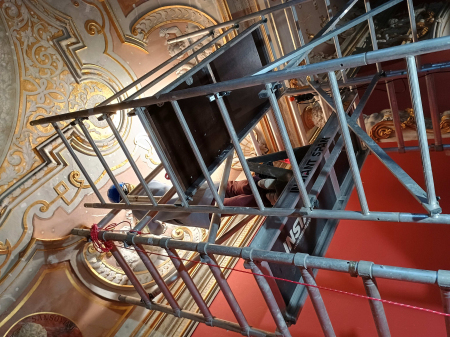 Zdjęcie przedstawia jedną osobę na rusztowaniu we wnętrzu muzealnym podczas prac konserwatorskich